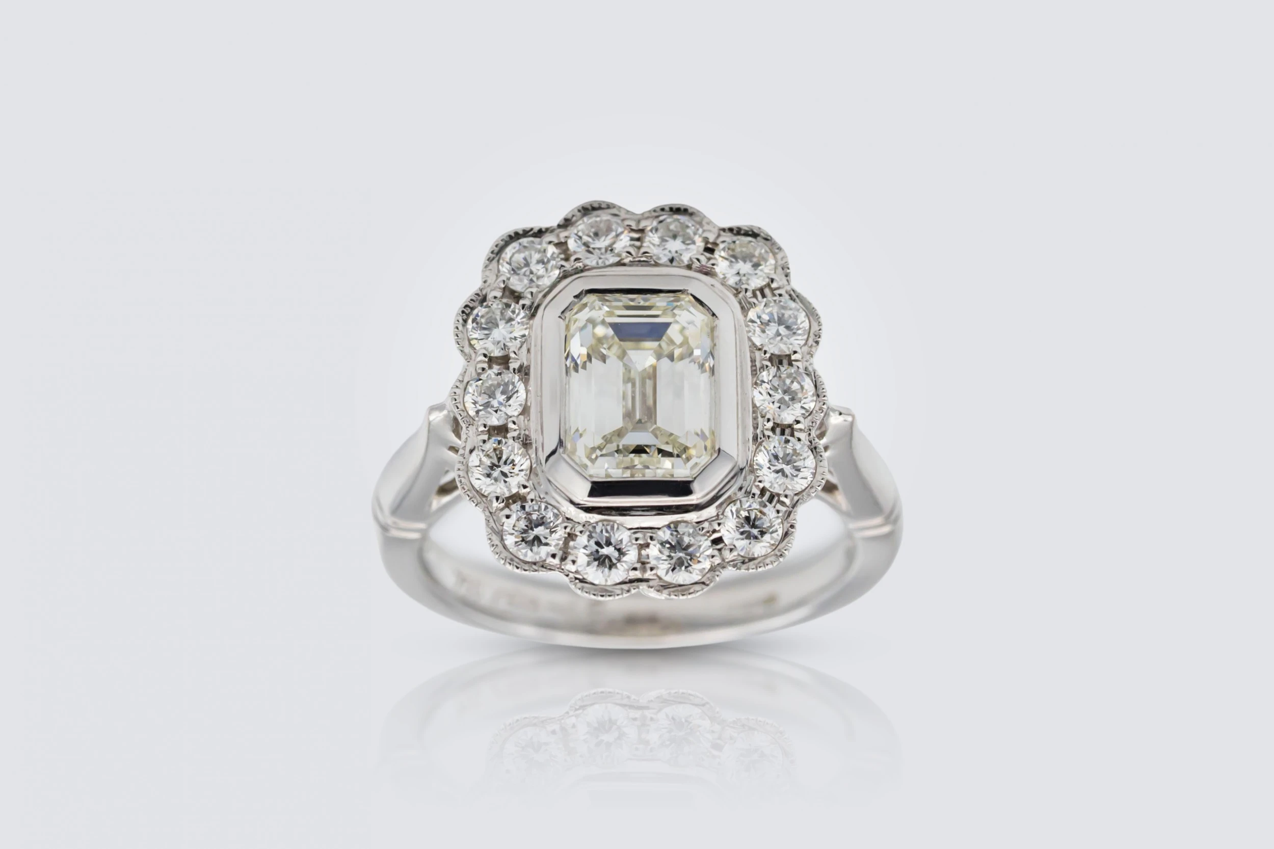 18ct White Gold 1.50ct Emerald and 0.65ct Diamond Rubover Halo Ring Size K